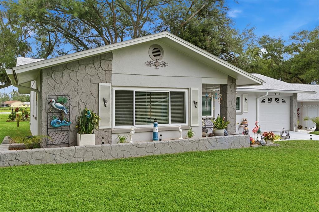 A single-story house with a gray stone facade, a front porch, and a manicured lawn — 8715 BENTON DRIVE, PORT RICHEY, FL