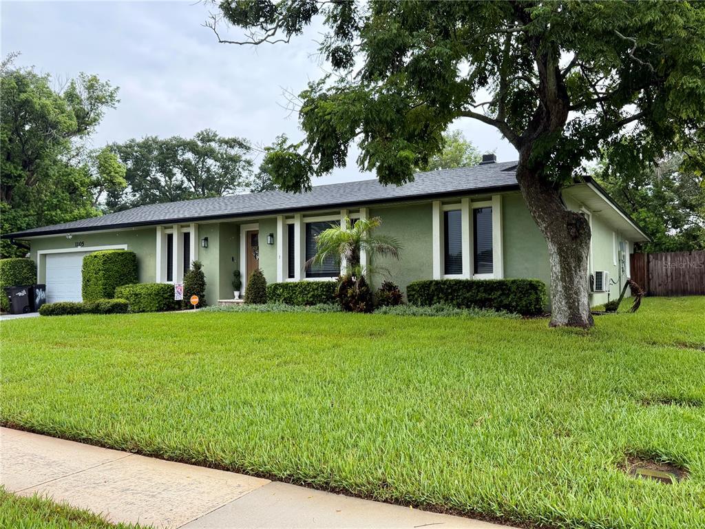 A single-story house with green stucco walls, a dark roof, and a large front lawn — 1105 DORIS STREET, ALTAMONTE SPRINGS, FL