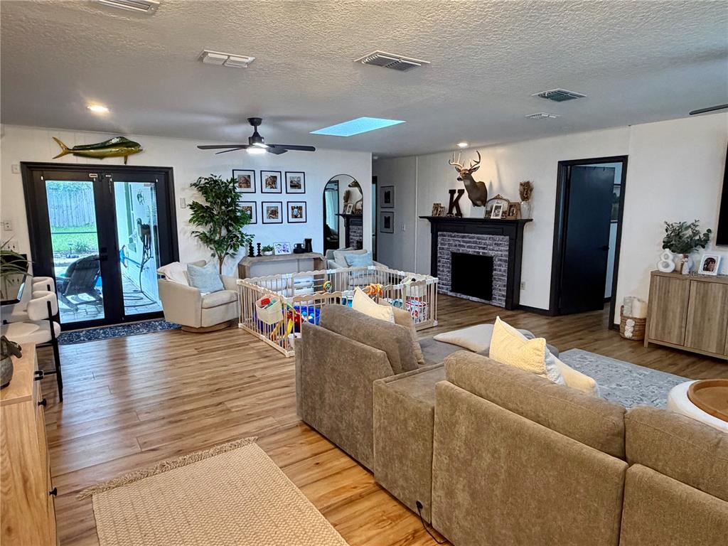 A living room features wood-look flooring, a fireplace with a deer mount, and a playpen — 1105 DORIS STREET, ALTAMONTE SPRINGS, FL