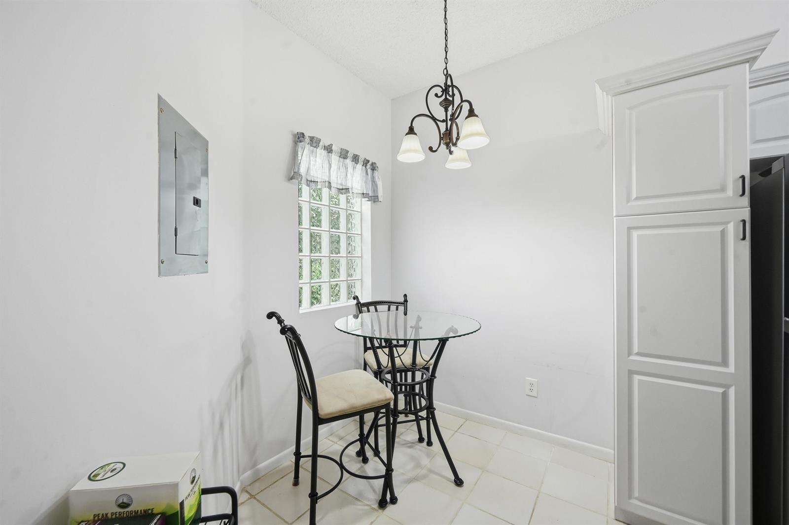 A small dining nook features a glass-topped table, two chairs, and a glass block window — 5395 Firenze Drive # K, Boynton Beach FL 33437, BOYNTON BEACH, FL