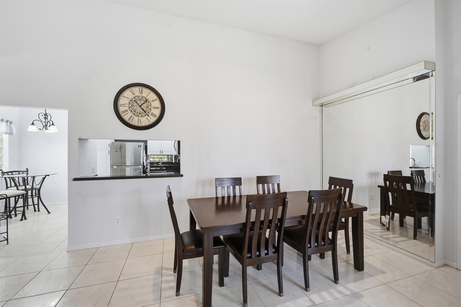 A dining room features a dark wood table with six chairs and a large wall mirror — 5395 Firenze Drive # K, Boynton Beach FL 33437, BOYNTON BEACH, FL