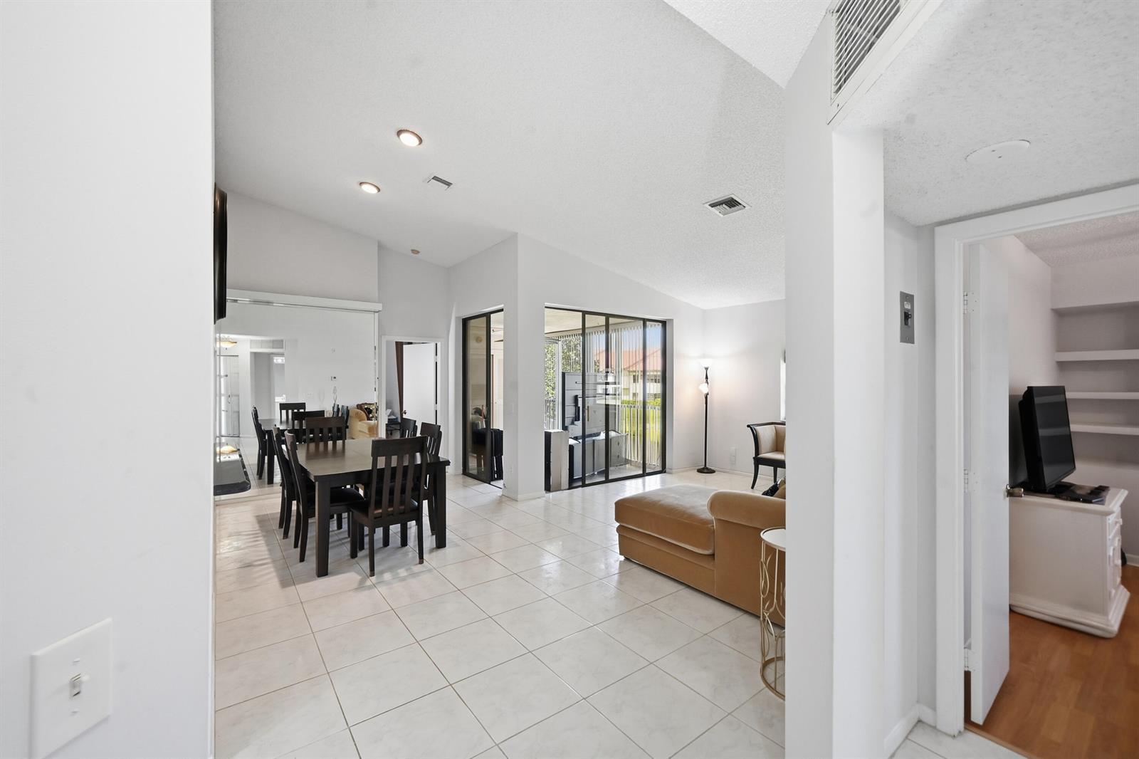 A bright open-concept living and dining area features white tile floors and vaulted ceilings — 5395 Firenze Drive # K, Boynton Beach FL 33437, BOYNTON BEACH, FL