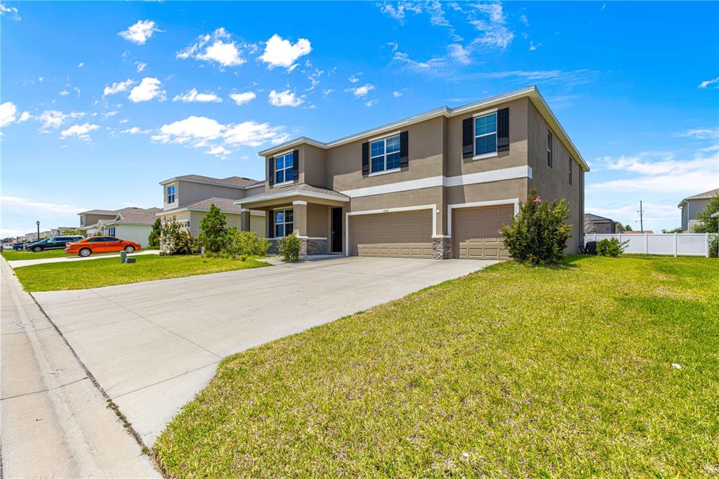 A two-story suburban house with a tan stucco exterior, a concrete driveway, and two garages — 8142 SW 59TH AVENUE, OCALA, FL