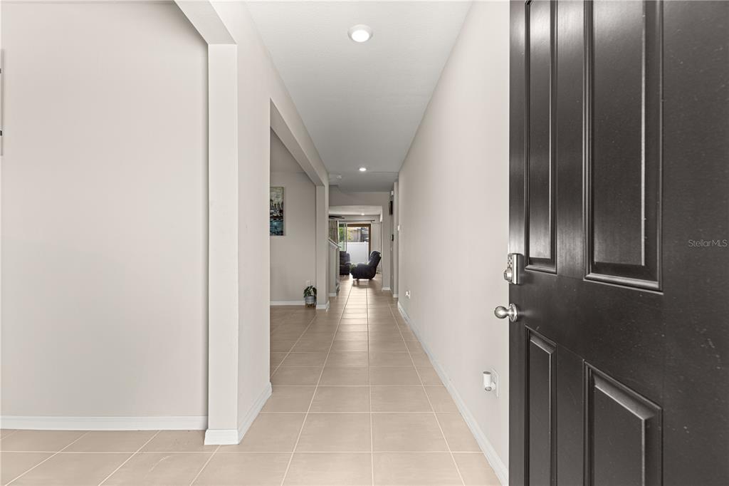A view from an open front door looking down a tiled hallway into a living area — 8142 SW 59TH AVENUE, OCALA, FL