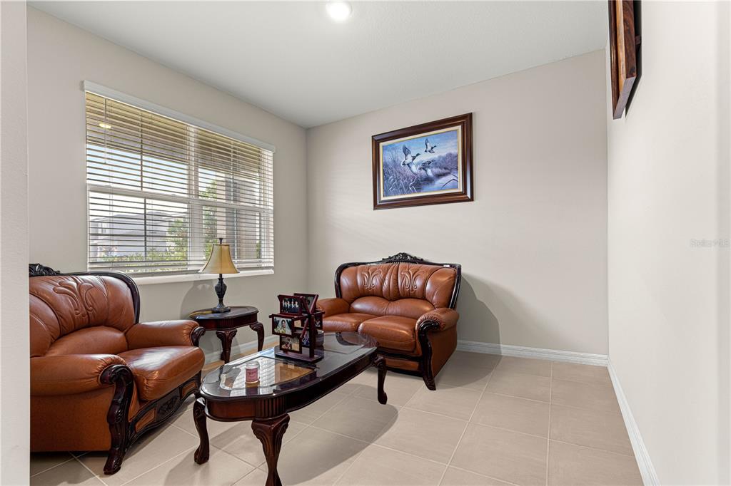 A living room features tan tile floors, two brown leather sofas, and a framed painting — 8142 SW 59TH AVENUE, OCALA, FL