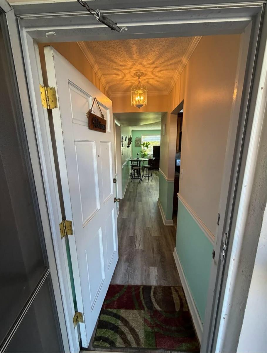An open front door reveals a hallway with light green wainscoting and wood-look flooring — 2770 S Garden Drive # 107, FL 33461, FL