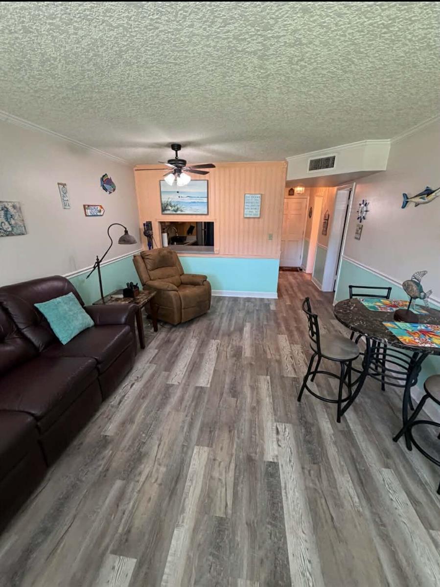 A living and dining area features wood-look flooring, a brown leather sofa, and a recliner — 2770 S Garden Drive # 107, FL 33461, FL