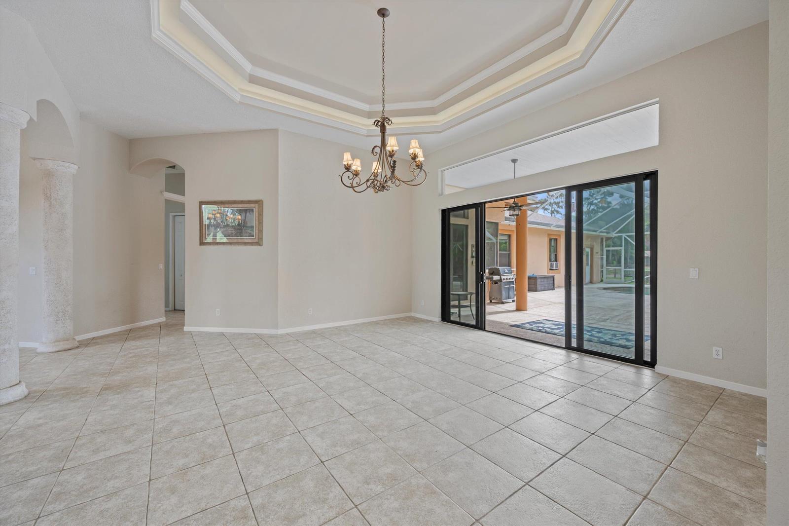 A dining room with tile floors, a tray ceiling, a chandelier, and sliding glass doors — 2910 Doe Trail, Loxahatchee FL 33470, LOXAHATCHEE, FL