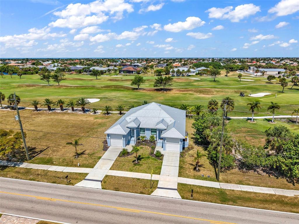 An aerial view shows a single-story house with a metal roof facing a golf course — 3451 BAL HARBOR BOULEVARD, PUNTA GORDA, FL