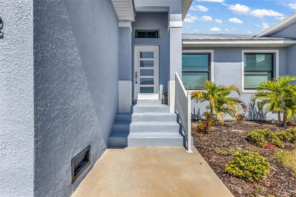 A blue house exterior features a concrete walkway leading to a white front door — 3451 BAL HARBOR BOULEVARD, PUNTA GORDA, FL