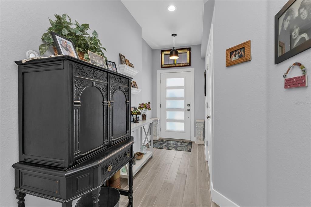 A bright entryway features wood-look tile flooring, a black cabinet, and a modern front door — 3451 BAL HARBOR BOULEVARD, PUNTA GORDA, FL