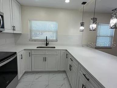 A modern kitchen features white cabinets, a white countertop, a sink, and pendant lighting — 270 W PINELOCH AVENUE, ORLANDO, FL