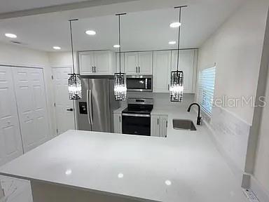 A modern kitchen features white cabinetry, stainless steel appliances, and a white quartz countertop island — 270 W PINELOCH AVENUE, ORLANDO, FL