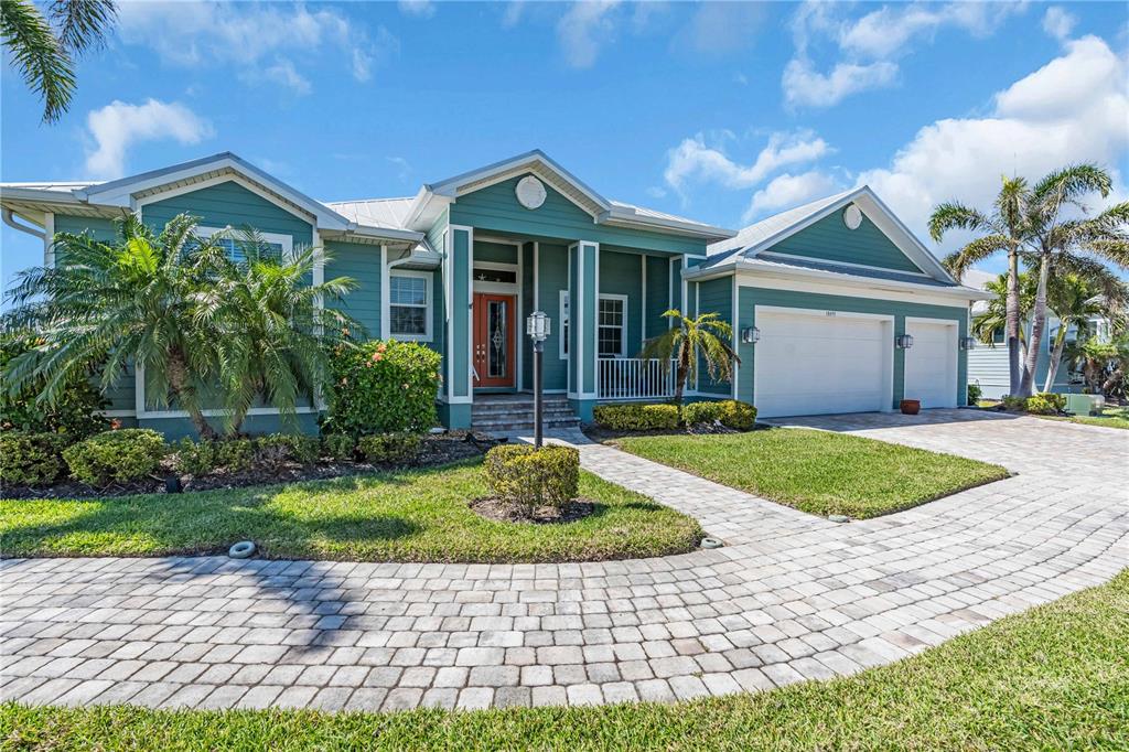A teal single-story house with a white garage, paved driveway, and palm trees — 18091 WOODEN SKIFF COURT, NOKOMIS, FL