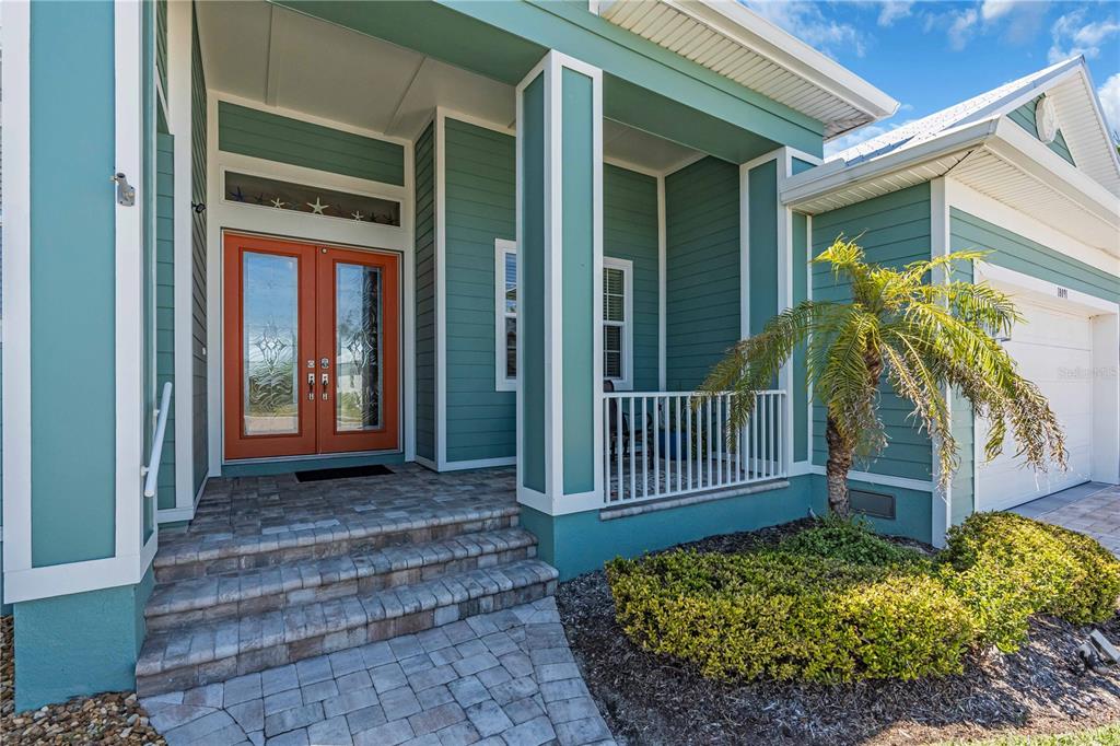 The exterior of a teal house features a stone walkway, double front doors, and porch — 18091 WOODEN SKIFF COURT, NOKOMIS, FL