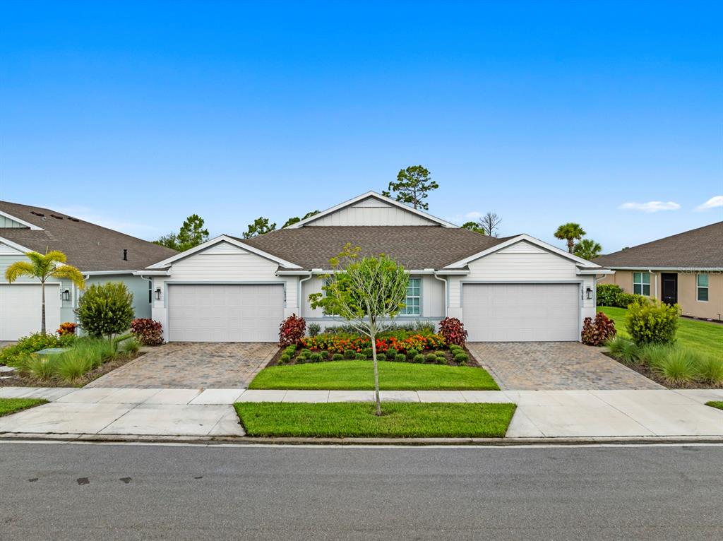 A duplex home with two garage doors, a landscaped front yard, and a paved driveway — 16974 HAWK COURT, PUNTA GORDA, FL