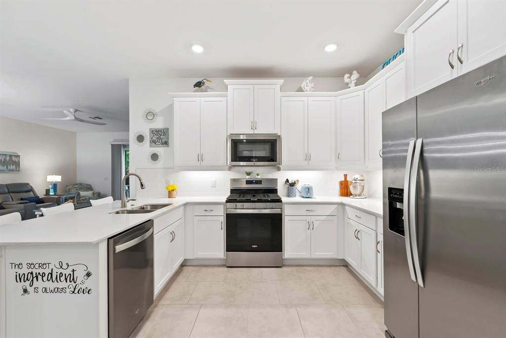 A kitchen with white cabinets, stainless steel appliances, and a large island with a sink — 16974 HAWK COURT, PUNTA GORDA, FL