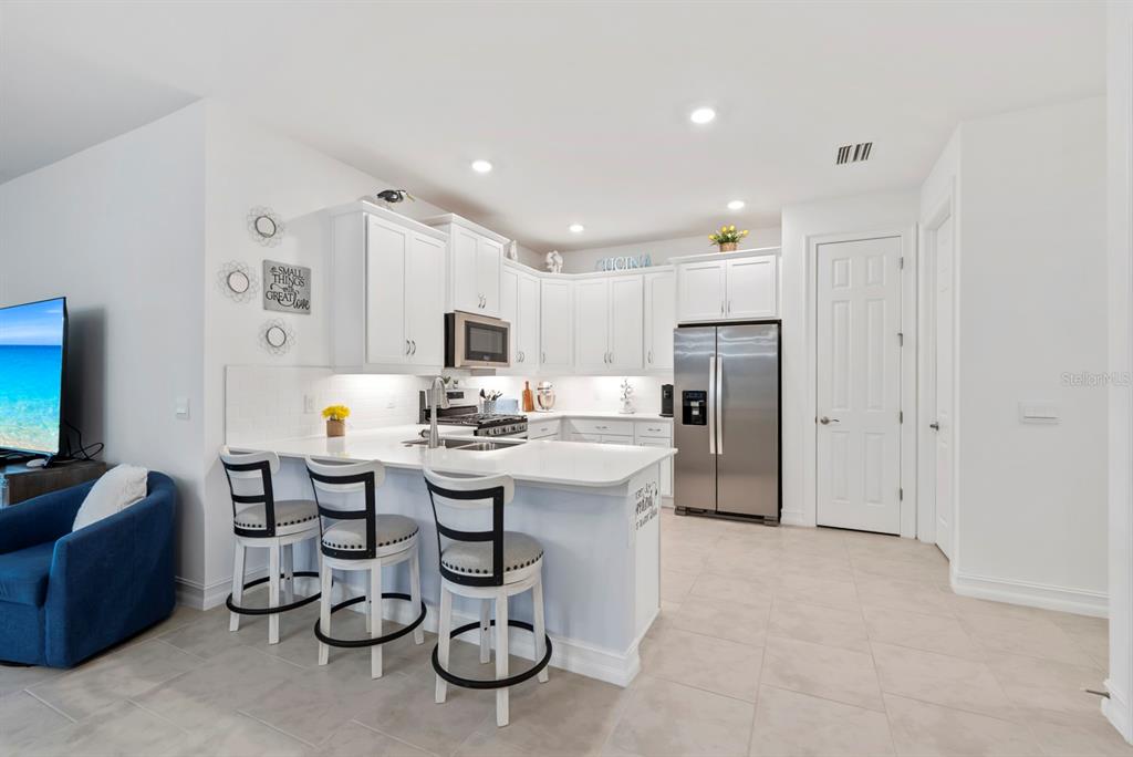 A kitchen features white cabinets, stainless steel appliances, a breakfast bar, and light tile flooring — 16974 HAWK COURT, PUNTA GORDA, FL