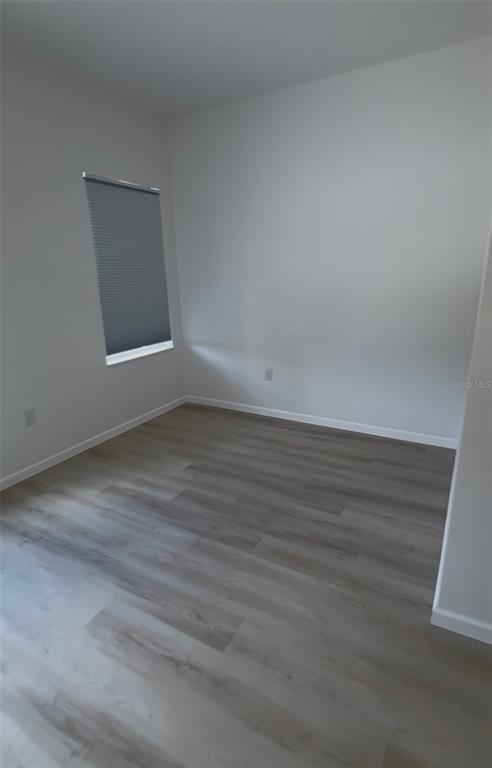 An empty room features light gray wood-look flooring, white walls, and a single window — 14665 SW 22ND PLACE, OCALA, FL