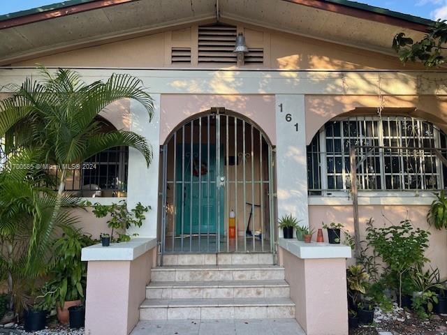 The exterior of a house features a gated front entrance with stairs and arched windows — 161 NW 35th St, Miami FL 33127, MIAMI, FL