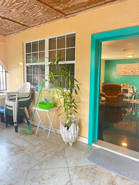 A covered patio features a tiled floor, a potted plant, a birdcage, and stacked chairs — 161 NW 35th St, Miami FL 33127, MIAMI, FL