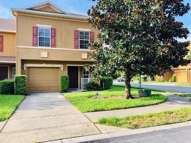 A two-story tan townhouse with a single-car garage and a large tree in the yard — 3522 CARUSO PLACE, OVIEDO, FL