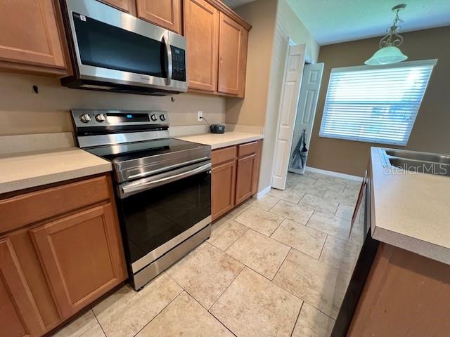 A kitchen features wood cabinets, stainless steel appliances, and light-colored tile flooring — 3522 CARUSO PLACE, OVIEDO, FL