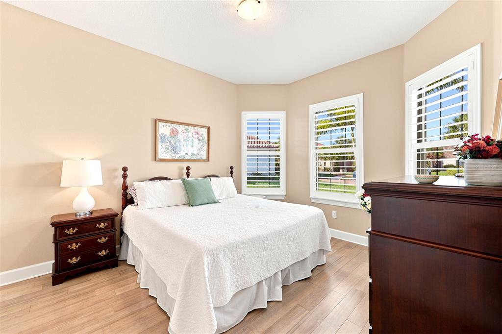 A bedroom features a queen bed, light wood flooring, white furniture, and large windows — 4616 STICKLEY COURT, PALMETTO, FL
