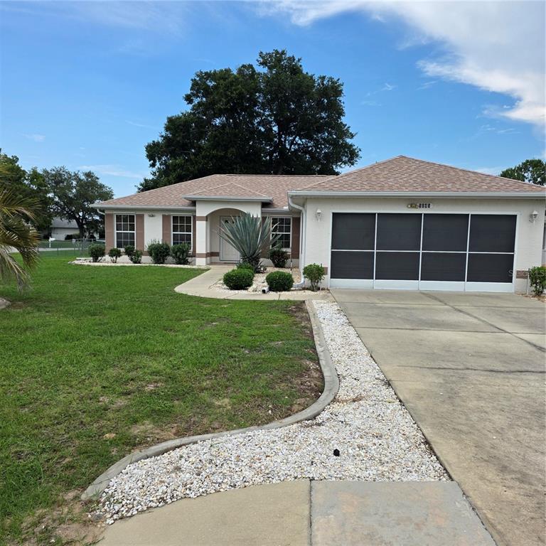 A single-story house with a beige exterior, a shingled roof, and a screened garage door — 5045 NW 32ND PLACE, OCALA, FL