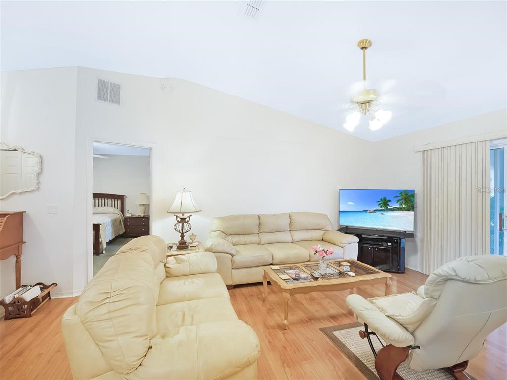A living room features light-colored leather furniture, a wooden coffee table, and wood-look flooring — 5045 NW 32ND PLACE, OCALA, FL