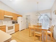 A kitchen with light wood cabinets, white appliances, and a dining table with four chairs — 5045 NW 32ND PLACE, OCALA, FL