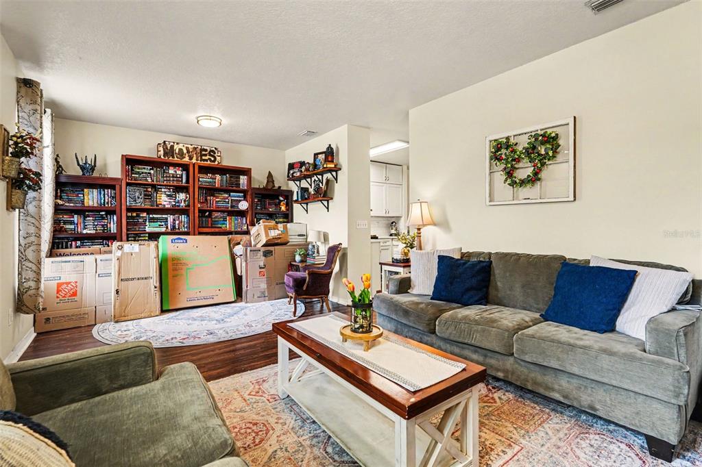 A living room features a gray sofa, a purple armchair, and a television on a console — 30153 BARNABY LANE, WESLEY CHAPEL, FL