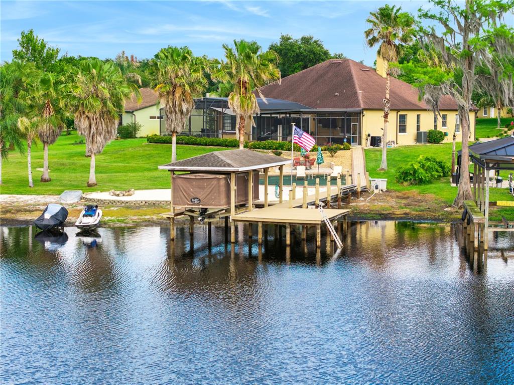 A waterfront house with a boat dock, pool, and palm trees on a grassy lawn — 11325 PRESTON COVE ROAD, CLERMONT, FL