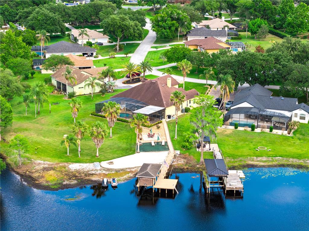 An aerial view shows a waterfront house with a pool, dock, and boat slips — 11325 PRESTON COVE ROAD, CLERMONT, FL