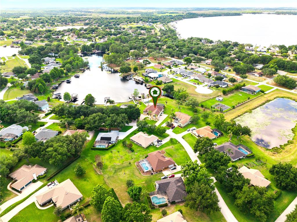 An aerial view shows a residential neighborhood with houses, swimming pools, and a lake — 11325 PRESTON COVE ROAD, CLERMONT, FL