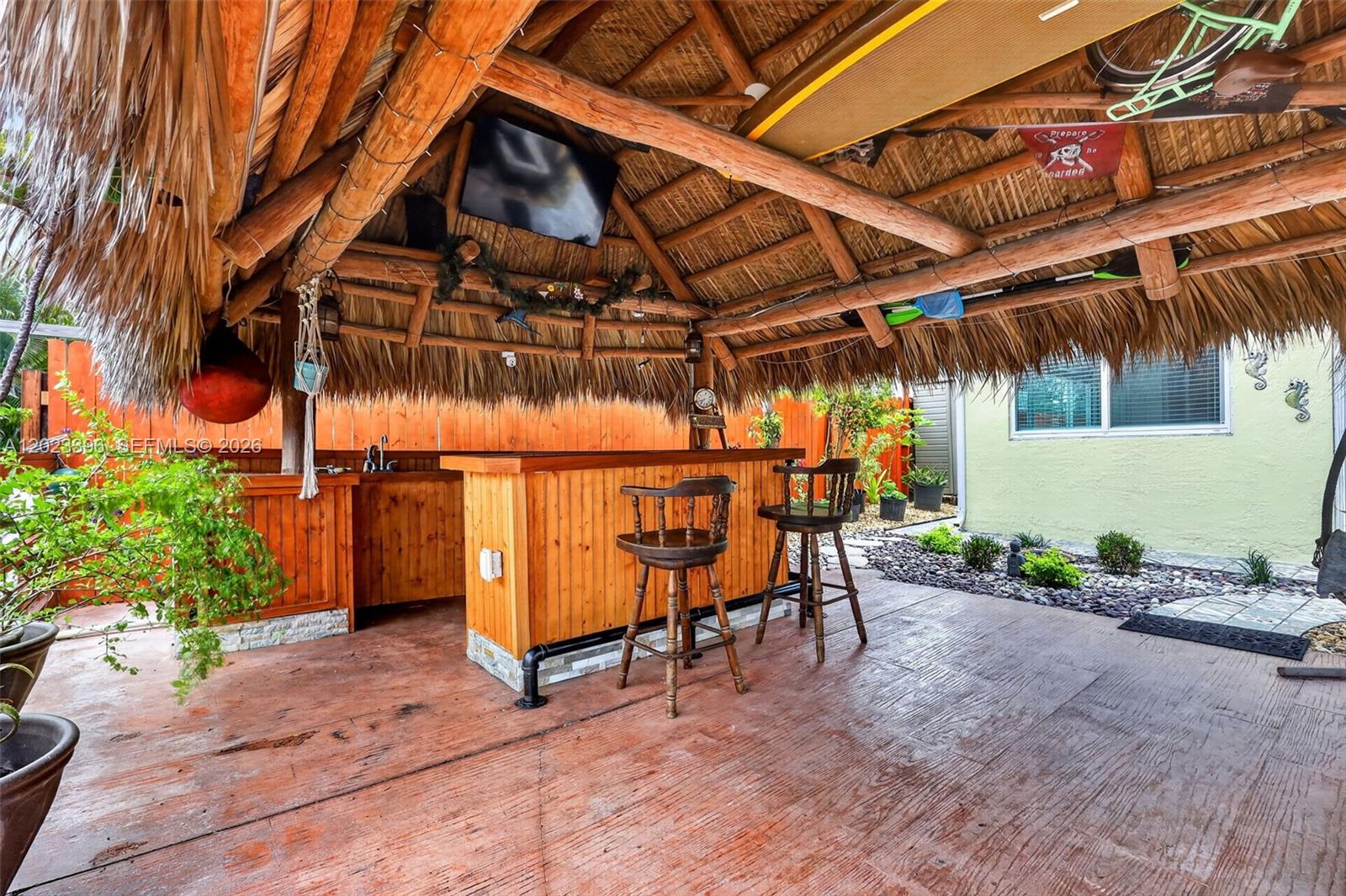 An outdoor tiki bar features a thatched roof, wooden counter, and two bar stools — 2730 Sherman St, Hollywood FL 33020, HOLLYWOOD, FL