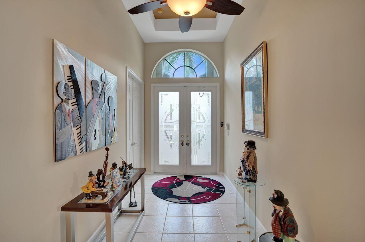 A tiled entryway features a double front door, a ceiling fan, and decorative wall art — 1775 Annandale Circle, Royal Palm Beach FL 33411, ROYAL PALM BEACH, FL