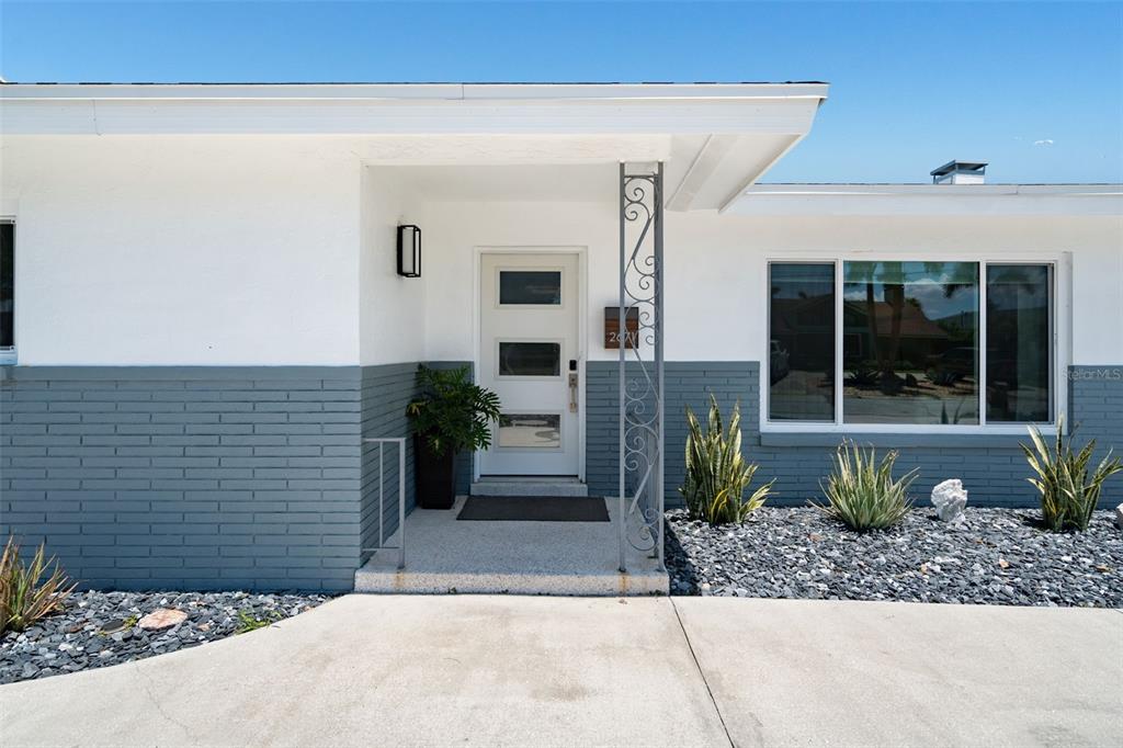 The exterior of a house features a white and gray facade with a front door — 2671 W BAY ISLE DRIVE SE, ST PETERSBURG, FL