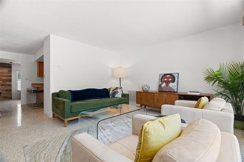 A living room features a green sofa, white armchairs, a glass coffee table, and terrazzo flooring — 2671 W BAY ISLE DRIVE SE, ST PETERSBURG, FL