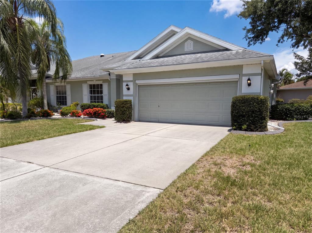 A single-story house with a light green exterior, a two-car garage, and a concrete driveway — 923 OXFORD PARK DRIVE UNIT 81, SUN CITY CENTER, FL