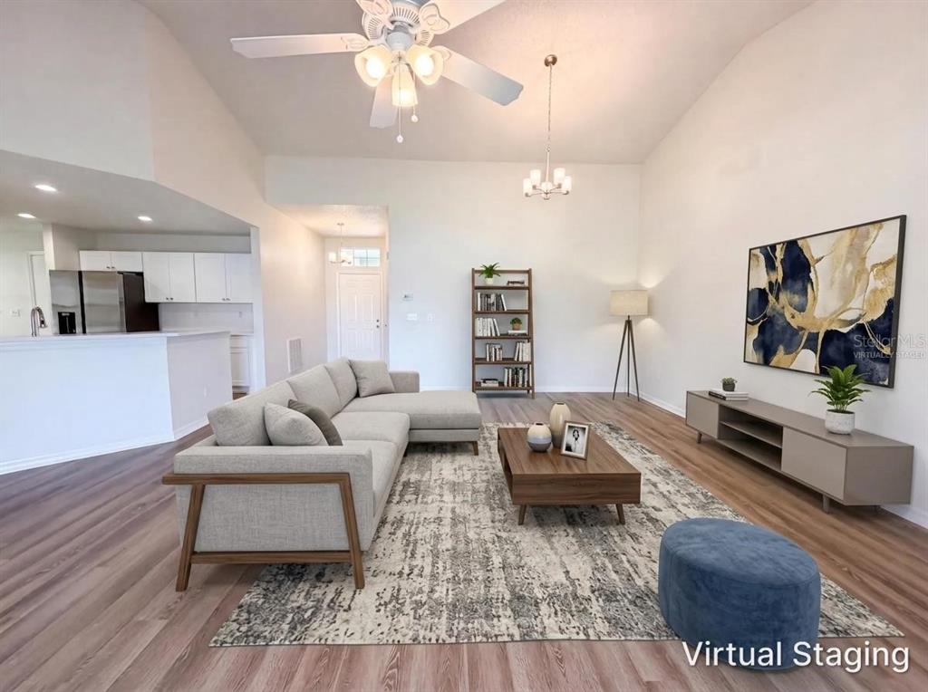 A living room with wood-look flooring, a sectional sofa, and a television on the wall — 923 OXFORD PARK DRIVE UNIT 81, SUN CITY CENTER, FL