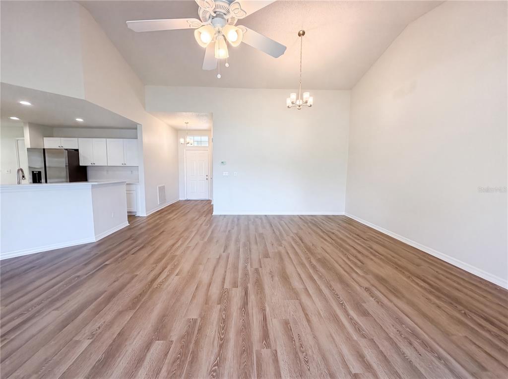 A spacious living area features light wood-look flooring, a vaulted ceiling, and an adjacent kitchen — 923 OXFORD PARK DRIVE UNIT 81, SUN CITY CENTER, FL