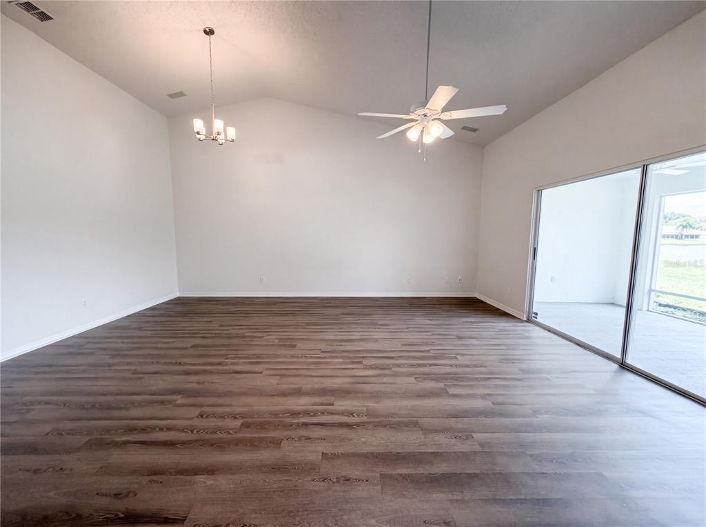 A spacious living room features vaulted ceilings, wood-look flooring, a ceiling fan, and sliding doors — 923 OXFORD PARK DRIVE UNIT 81, SUN CITY CENTER, FL
