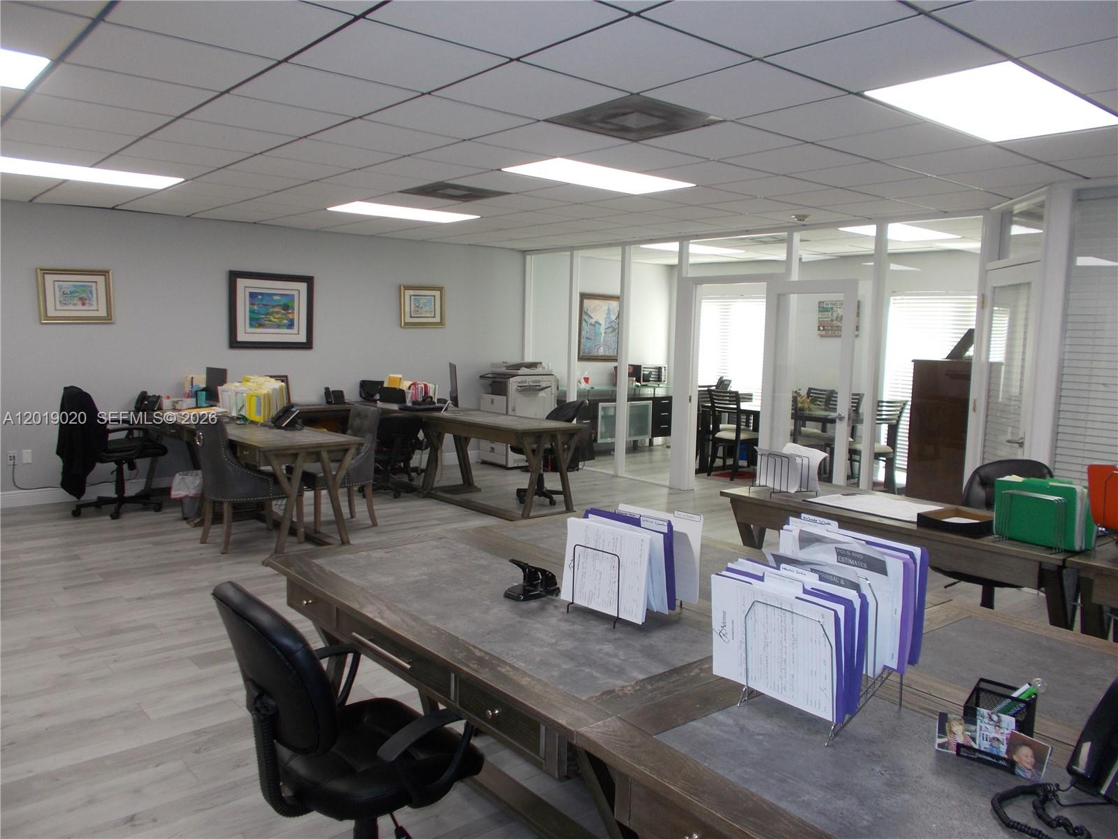 An office space features multiple wooden desks, gray flooring, and a drop ceiling with lights — 13055 SW 42nd St # 204, Miami FL 33175, MIAMI, FL