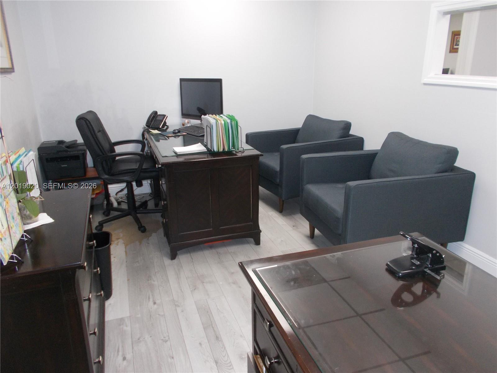 An office room features two dark wood desks, two armchairs, and light wood-look flooring — 13055 SW 42nd St # 204, Miami FL 33175, MIAMI, FL