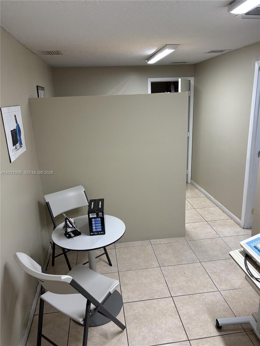 A small waiting area features a round table, two chairs, and a partial privacy wall — 1750 W 39th Pl # 1007, Hialeah FL 33012, HIALEAH, FL