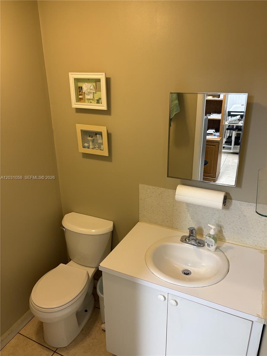 A bathroom features a white vanity, a toilet, and two framed pictures on the wall — 1750 W 39th Pl # 1007, Hialeah FL 33012, HIALEAH, FL