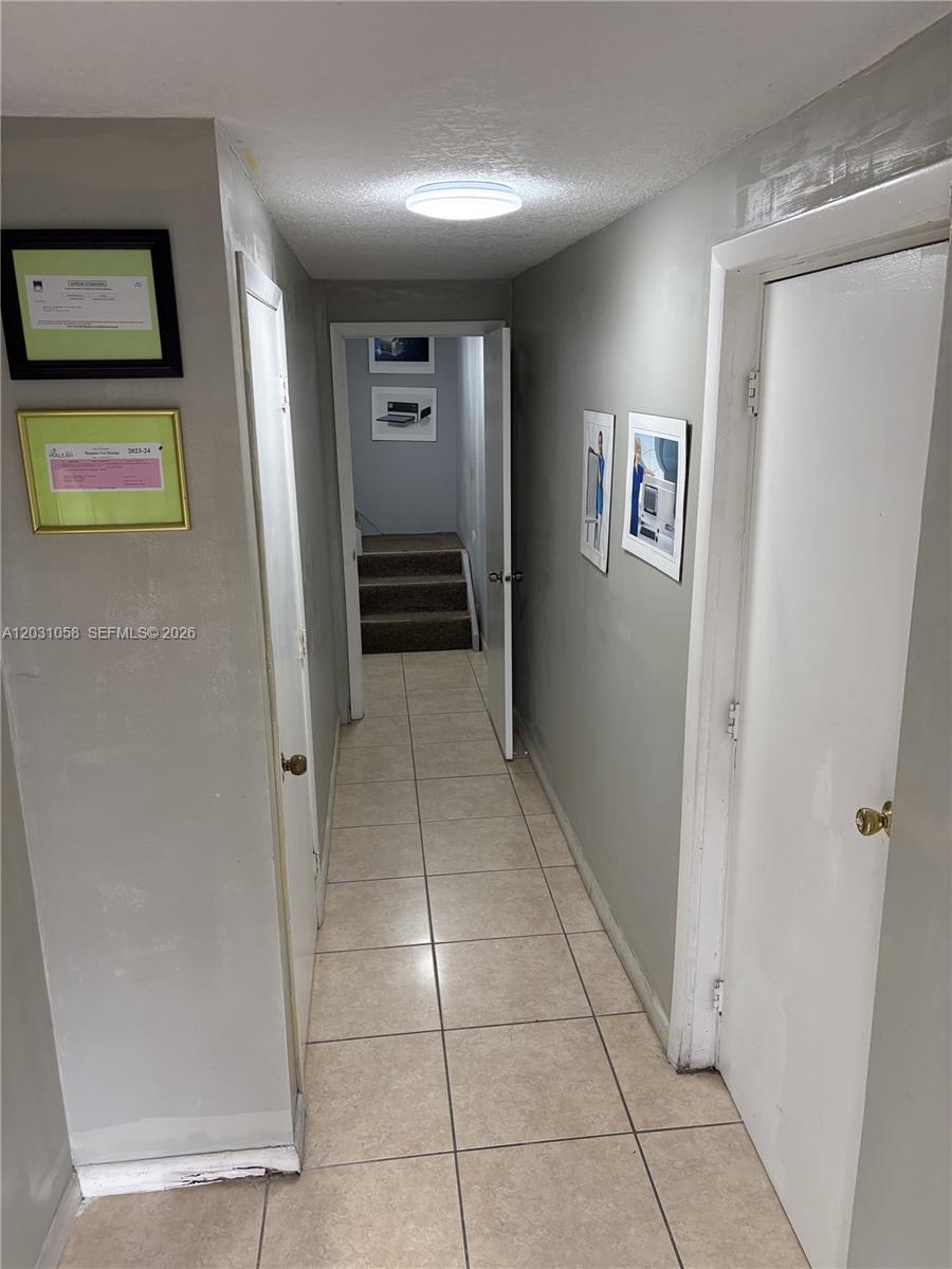 A tiled hallway leads to a doorway with stairs visible in the background — 1750 W 39th Pl # 1007, Hialeah FL 33012, HIALEAH, FL