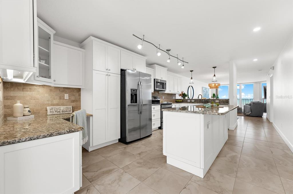A white kitchen features granite countertops, stainless steel appliances, and a central island — 2600 GULF DRIVE N UNIT 33, BRADENTON BEACH, FL
