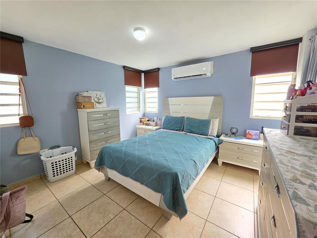 A bedroom features light blue walls, a queen bed, tiled floors, and light-colored furniture — 838 IMPERIAL, JUANA DIAZ, PR